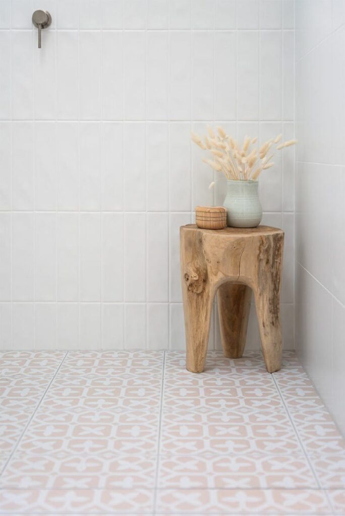 Encaustic tile floor with a timber stool in a white bathroom