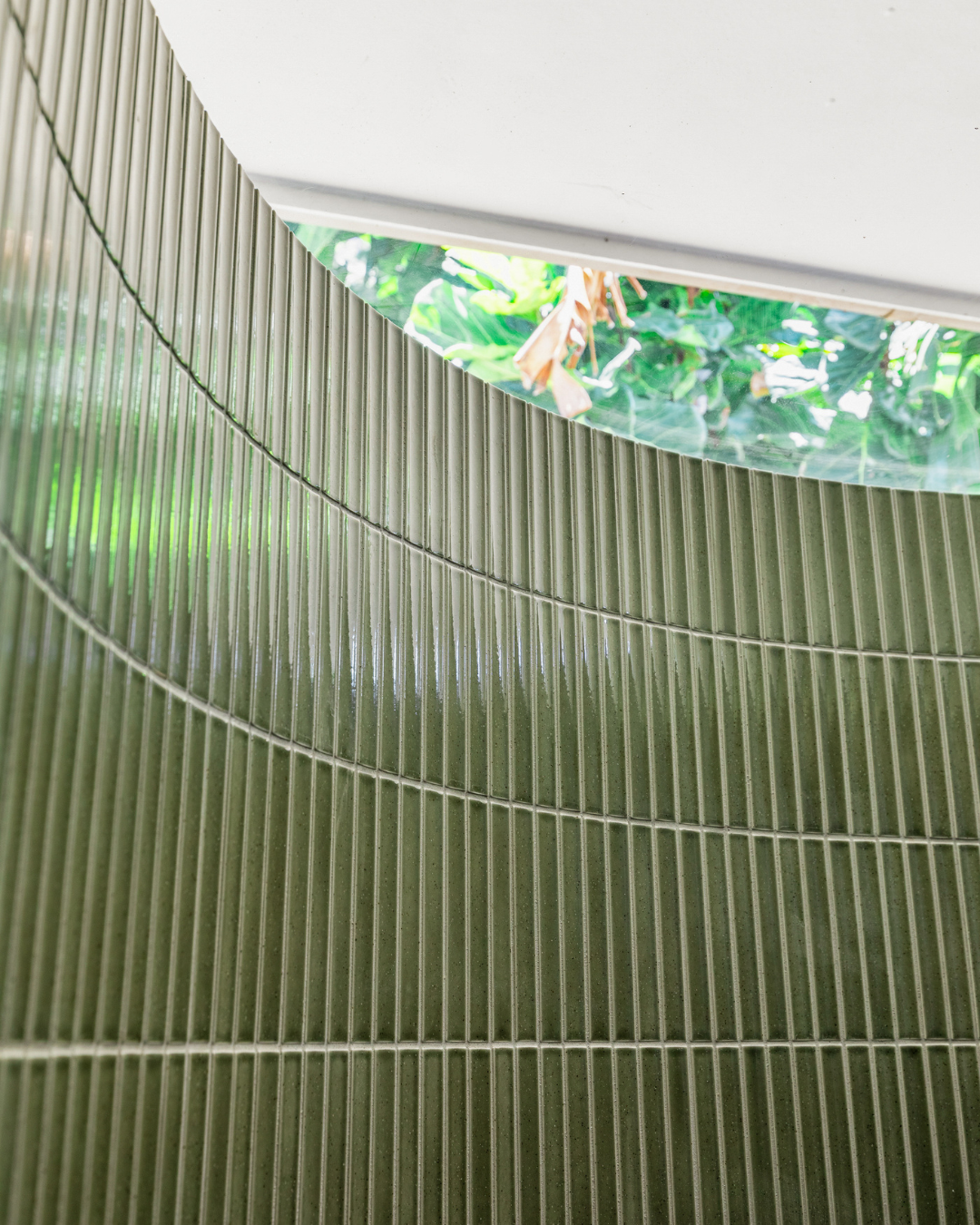 Close-up of a curved shower wall in Blade Kit Kat Forest green finger tiles